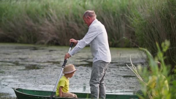 Рыбалка, дедушка с внуками плавает с берега на лодке во время активного отдыха в сельской местности — стоковое видео