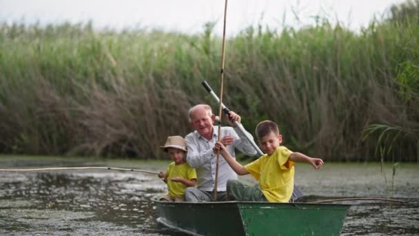 Alte Eltern mit Paddel und Kinder mit Stöcken im Boot beim Angeln, Familie verbringt Zeit zusammen auf einem Teich im Schilf — Stockvideo