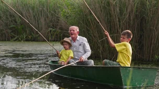 Abuelo cariñoso, cuidado viejo padre pasa tiempo con los niños mientras pesca en barco en el río durante unas vacaciones de verano — Vídeos de Stock