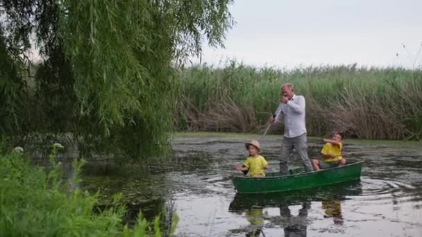 Kinder mit Großvater auf dem Boot winken Hallo, Großmutter grüßt die Familie vom Fischen vor dem Hintergrund der schönen Natur in der Landschaft — Stockvideo