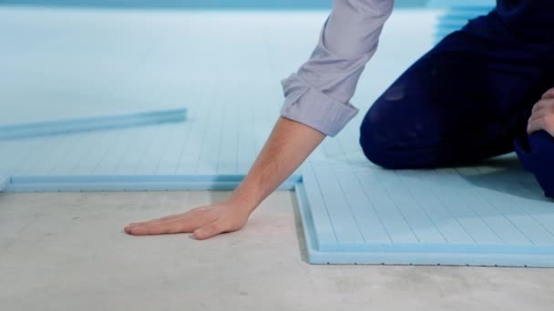 Construtor masculino coloca isolamento e verifica fechaduras de isopor toca concreto com a mão comparando o calor do chão — Vídeo de Stock