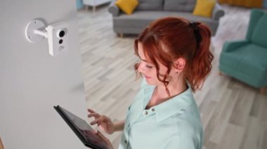 Kablosuz ev güvenlik sistemi, akıllı genç bir kadının kamera kurması ve kontrol etmesi apartmandaki tablette işe yarıyor.