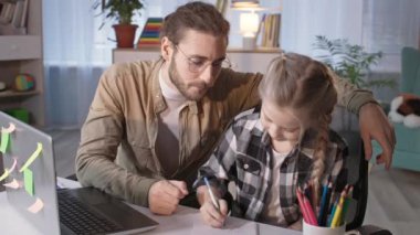 Veliler ve kızları online bir ders sırasında evde otururken ev ödevi yapıyorlar.