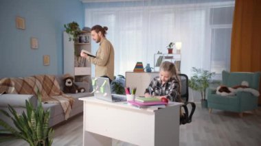 Erkekler, karantina altındaki çocuklara öğretirken kızların ödevlerini yapmasına ve dikte etmesine yardım eder.