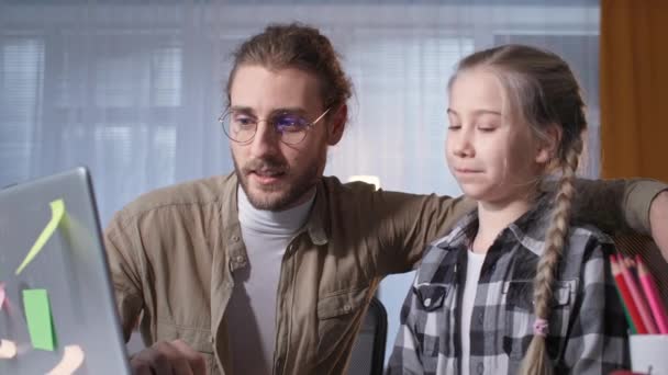 Apa és a női gyermek a házi feladatot együtt tanár ül online laptop otthon világjárvány idején — Stock videók
