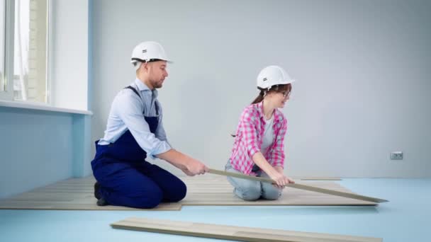 Männliche und weibliche Bauteam in Schlitzen legen Laminatboden während der Renovierung und Heimwerker, gib mir fünf — Stockvideo
