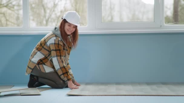 L mulher no capacete de proteção estabelece laminado no chão durante a renovação no apartamento — Vídeo de Stock