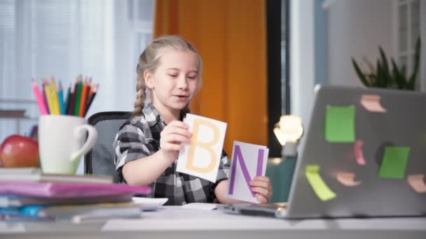 女性の子供はノートパソコンでのビデオ通話で教師との遠隔授業を学びます — ストック動画