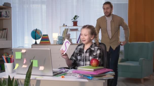 Pai masculino ajuda sua filha a fazer lição de casa com professor on-line usando webcam no laptop em casa durante a quarentena — Vídeo de Stock