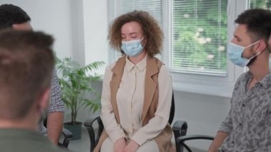 Virüs ve enfeksiyondan korunmak için maske takan bir grup insan grup terapisi sırasında endişelerini ve endişelerini paylaşıyor.