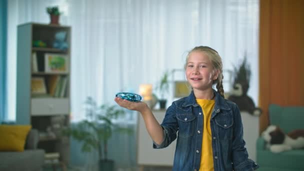 インタラクティブなおもちゃ小さな女の子の手の上にホバリング無人機が飛び去る女性の子供は家で親指を示しています — ストック動画