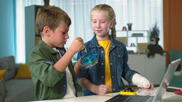 Дети и технологии, умный мальчик с инструментом и девочка с гипсовым гипсом под рукой изучают работу квадрокоптера дома — стоковое видео
