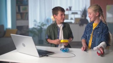 Çocuk eğlencesi, aletleri olan aktif çocuklar USB kablosuyla laptopa bağlı mini kuadkopteri tamir etmek için masaya gidin.