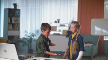 Uçan oyuncaklı mutlu çocuklar, alçılı kız ve oğlan içeride küçük drone fırlatıyor ve mutlu bir şekilde oynuyorlar.