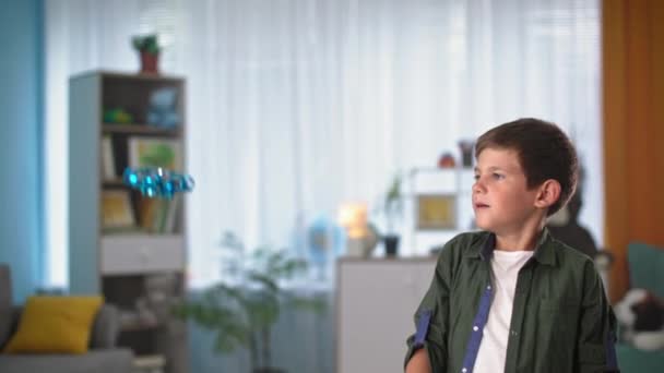 Attrayant garçon jouer avec jouet volant, portrait enfant lance mini quadrocopter à l'intérieur et montre joyeusement pouces vers le haut — Video