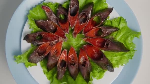 海味，鱼子酱咸鱼的美味多汁片，放在生菜叶上，放在盘子里，在浅色背景下纺丝 — 图库视频影像