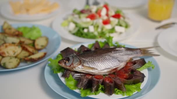 Healthy lunch, sea fish cut into pieces with caviar on white plate stands background of dishes during family dinner — Stock Video