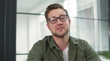 Uzaktan iletişim, gülümseyen genç adam bilgisayardan müşteri ya da arkadaşla görüntülü konuşma yapıyor kapalı bir masada kameraya bakıyor.