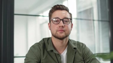 Çevrimiçi iş görüşmesi, genç adam bilgisayardaki video konferansını kullanarak çalışıyor, içeride oturuyor ve kameraya bakıyor.