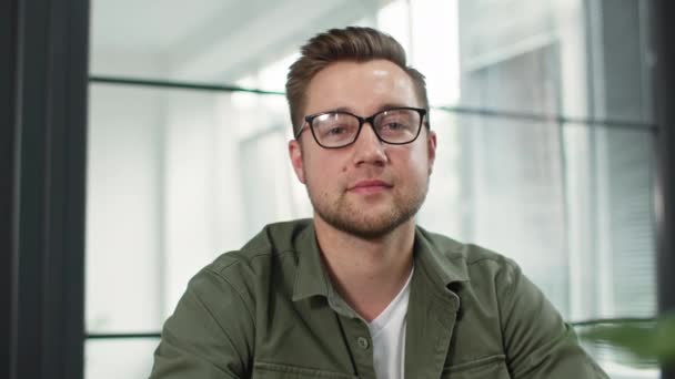 Fjärrintervju, ung man med glasögon kommunicerar med rekryterande chef via videolänk på laptop när du sitter i rummet, tittar på kameran — Stockvideo