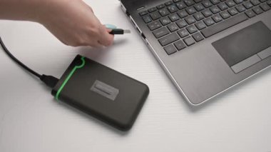 Kadın eli, hafif arka planda taşınabilir bir bilgisayara USB flaş bellek yerleştirir.