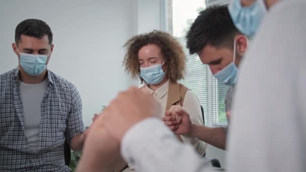 기도를 하고, 의료 마스크를 쓰고 있는 젊은 남녀들은 친구들의 손을 잡고 눈을 감은 채 기도를 하고 있습니다. — 비디오