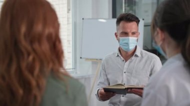 Genç adam önlem alıyor ve Hıristiyan erkek ve kadınlardan oluşan bir grup çemberde otururken yüzüne tıbbi maske takıyor.