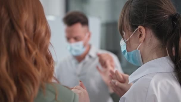 Christine, jeune équipe d'hommes et de femmes portant des masques médicaux se tiennent par la main pendant le culte et la prière assis en cercle, gros plan — Video