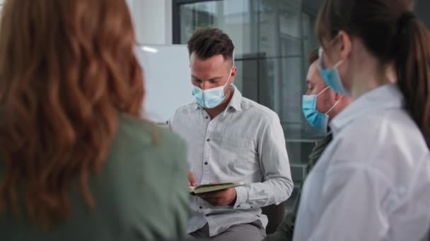 Groupe chrétien d'hommes et de femmes portant des masques médicaux observer les précautions tout en adorant Dieu et la lecture de la Bible tout en étant assis dans un cercle — Video