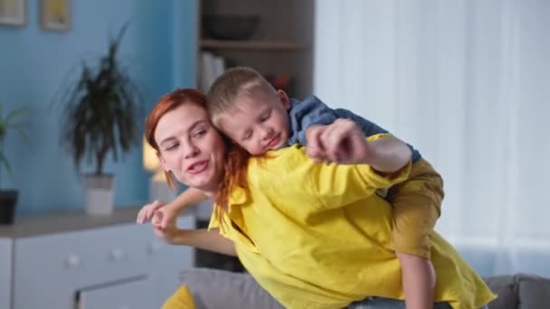 기쁨에 넘치는 어린 가족의 어린 어머니와 미소짓는 남자 아이가 함께 집에서 함께 쉬면서 비행기를 묘사하는 즐거움을 누리다 — 비디오