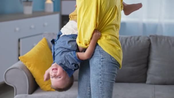 Maternità, amorevole mamma gioca con il suo piccolo figlio e lo rotola a testa in giù mentre appendere fuori a casa — Video Stock