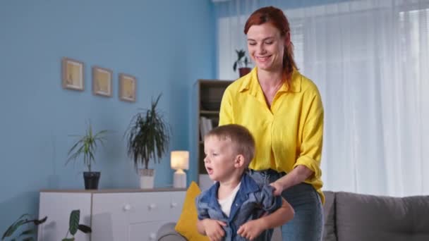 Motherhood, a caring female parent helps her son jump on a trampoline during home weekends — Stock Video