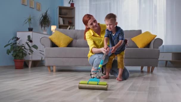 Relação pai-filho, menino adorável ajuda a sua mãe esfregona chão enquanto a limpeza da casa — Vídeo de Stock