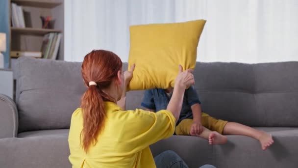 Carefree childhood, joyful boy has fun with his mother and fights pillows while relaxing at home — Stock Footage Carefree childhood, joyful boy has fun with his mother and fights pillows while relaxing at home Royalty Free Stock Footage