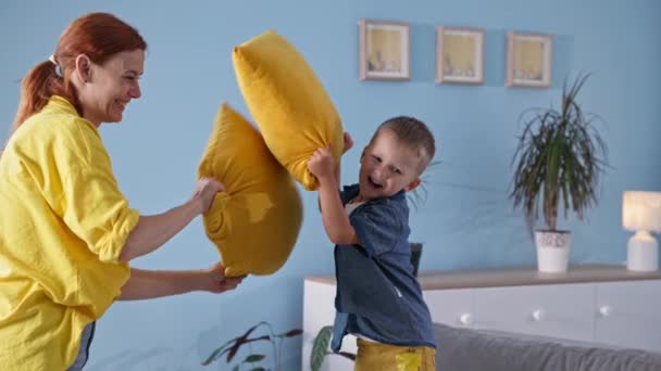 Grappige rust, respectabele moeder besteedt tijd met haar kleine zoon en vecht kussens terwijl opknoping out samen thuis — Stockvideo