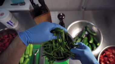 Mutfakta mavi eldiven giyen bir adam kabuklarından salatalık kabuklarını alıyor ve onları inceliyor. Birinci şahıstan en iyi görüntü. Büyük yakın çekim.