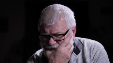 Yaşlı adam derin düşüncelere daldı. O gergin bir şekilde elini yüzüne uzatır ve parmaklarıyla sakalına dokunur, gerginliğine ihanet eder. Koyu arkaplan adamla çelişiyor.