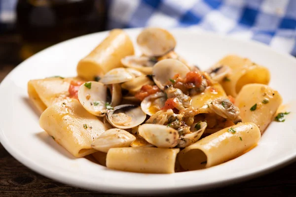 Paccheri pasta with clams on white plate close u