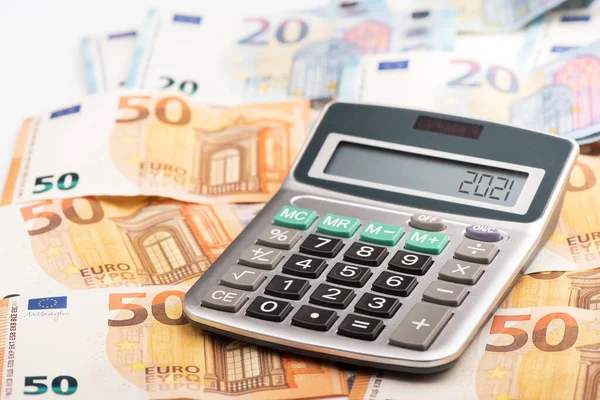 A calculator with euro money displaying Tax year 2021