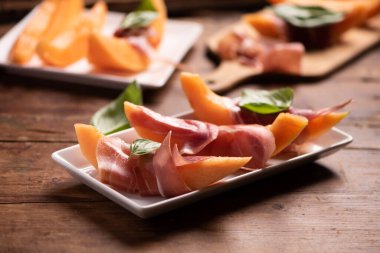 Taze kavun ve beyaz tabakta parma jambonu. Kapat.