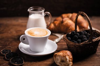 Kırsal ahşap bir masada ayçöreği olan kahve fincanı.