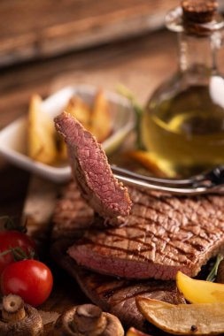 Dilimlenmiş orta pişmiş biftek ve patates kızartması.