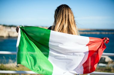 A tourist woman with italian flag looking the sea side. Italian supporter 