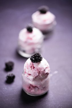 Blueberry and blackberry ice cream in bowl with frozen fruits close u