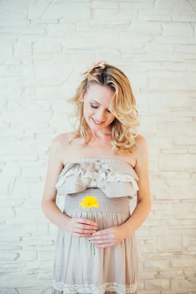 Una mujer embarazada feliz con flor amarilla —  Fotos de Stock