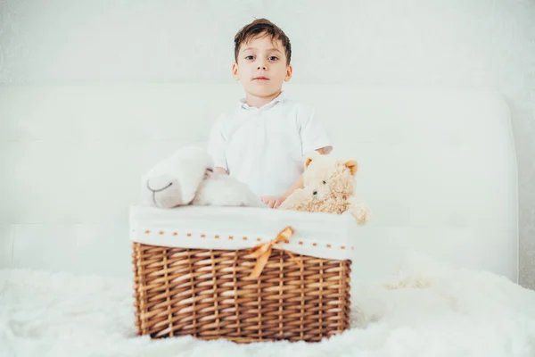 Menino escondido atrás de uma cesta com brinquedos macios — Fotografia de Stock