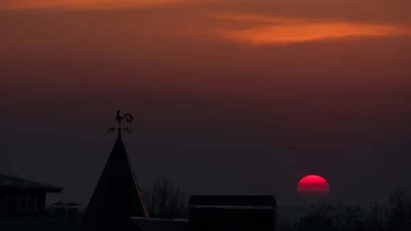 Magnificent sunset over the rooftops. wind indicator. red sun. — Stock Photo, Image