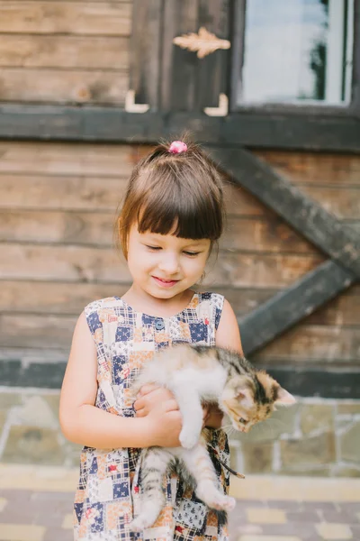 Fröhliches kleines Mädchen mit einer Katze im Arm — Stockfoto