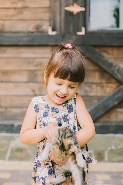 Fröhliches kleines Mädchen mit einer Katze im Arm — Stockfoto