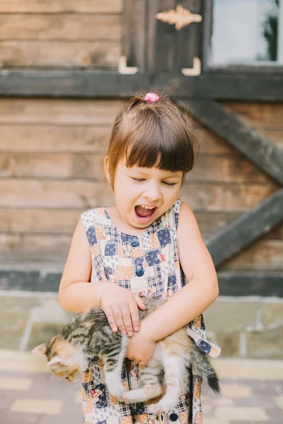 Fröhliches kleines Mädchen mit einer Katze im Arm — Stockfoto